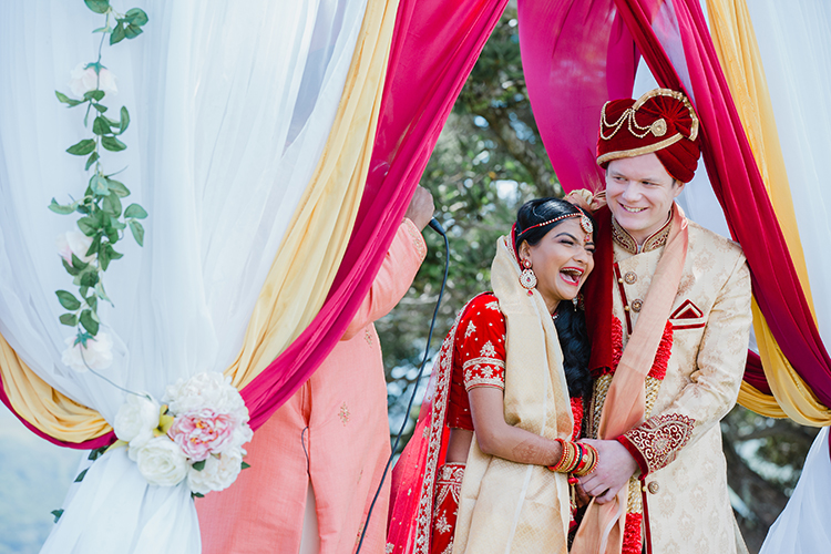 A wedding photo from a stunning fusion Indian wedding at Thomas's Bach on Waiheke Island in New Zealand. The mandap(ceremonial area) was set up outside with a stunning view int the background. Indian weddings are beautiful, bold and vibrant.. Photography by Mala Photography from Auckland.