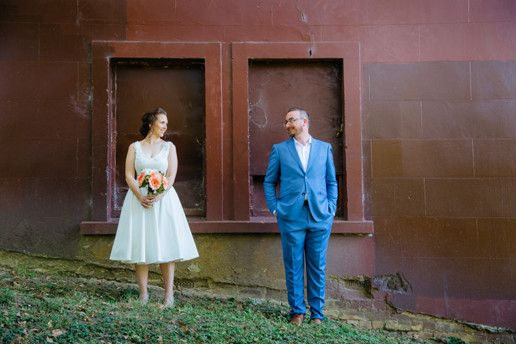 Auckland Wedding Photography by Mala Photography. A stylish, hipster couple standing next to each other and looking into each other's eyes. They are standing in front of a brown wall.