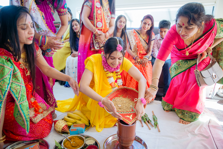 A photo of an Indian Bride dressed in a bright yellow sari performing pre-wedding Hindu rituals before her traditional Indian wedding. This photo was taken by Mala Photography, an Auckland based wedding, portrait and event photographer. 