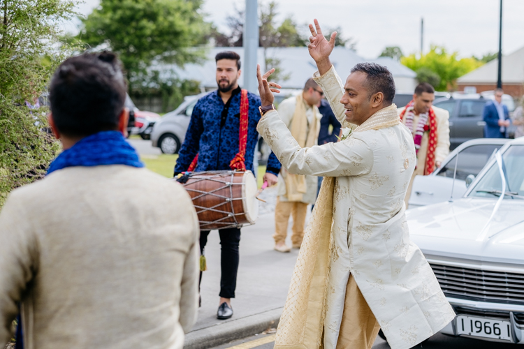 A groomsmen at a traditional Indian wedding at the Lincoln Events Centre in Christchurch dancing outside the venue before the wedding. A traditional Indian drummer is playing while the groomsmen and other guests dance.